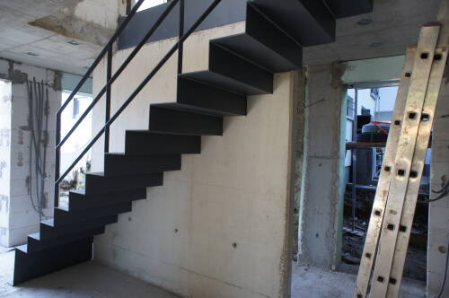 Gefaltete Blechtreppe, eingespannt in eine Sichtbetonwand